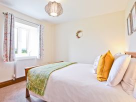 A bedroom with a bed and windows at Hillberry Cottage in Carnforth