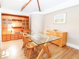 A dining room with a glass table and wooden chairs at The Mill House Apartment in 