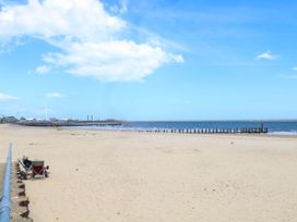 A view of a beach with a pier and wind turbine at The Mill House Apartment in 