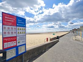 A beach scene with a sign and path at The Mill House Apartment Oulton Broad
