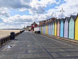 An outdoor area with colorful beach huts and a walkway by the beach at The Mill House Apartment Oulton Broad