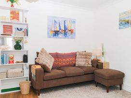 A living room with a sofa, cushions, shelf with books, and lamp at Elberry Cove View in Paignton
