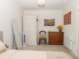 A bedroom with a bed, wardrobe, chair, and table at Elberry Cove View in Paignton