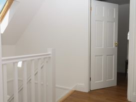 A hallway with a railing and an open door at Elberry Cove View in Paignton
