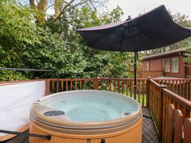 An outdoor hot tub with a parasol at Fir Tree Lodge, Coniston 3, White Cross Bay near Windermere