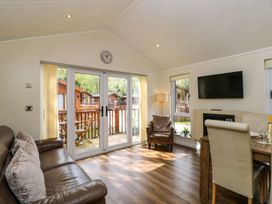 A living room with a sofa, chair, and dining area at Fir Tree Lodge, Coniston 3, White Cross Bay near Windermere