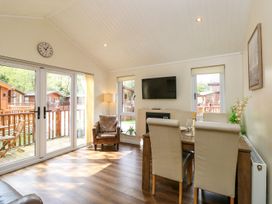 A living room with a dining table and tv at Fir Tree Lodge in Coniston 3, White Cross Bay near Windermere
