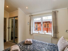 A bedroom with a bed and window at Fir Tree Lodge, Coniston 3, White Cross Bay near Windermere