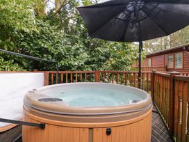 A hot tub on a wooden deck with an umbrella at Fir Tree Lodge, Coniston 3, White Cross Bay near Windermere