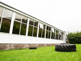 An outdoor view of a building with windows and a tire on the grass at Fir Tree Lodge, Coniston 3, White Cross Bay near Windermere