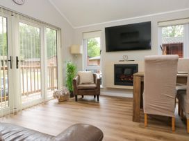 A living room with a fireplace and dining table at Fir Tree Lodge, White Cross bay on Windermere, Troutbeck Bridge
