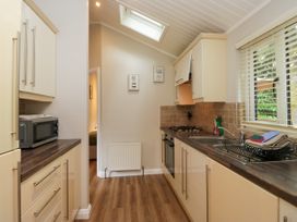 A kitchen with a stove and microwave at Fir Tree Lodge in White Cross bay on Windermere, Troutbeck Bridge