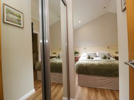 A bedroom with a bed and mirror at Fir Tree Lodge in White Cross bay on Windermere, Troutbeck Bridge