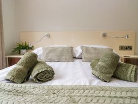 A bedroom with towels arranged on a bed at Fir Tree Lodge in White Cross bay on Windermere, Troutbeck Bridge