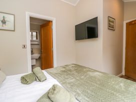 A bedroom with a bed and wall-mounted television at Fir Tree Lodge, White Cross bay on Windermere, Troutbeck Bridge