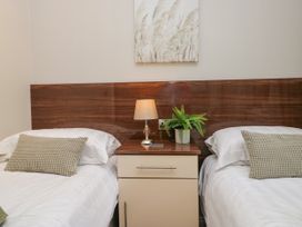 A bedroom with two beds and a bedside table at Fir Tree Lodge, White Cross bay on Windermere, Troutbeck Bridge