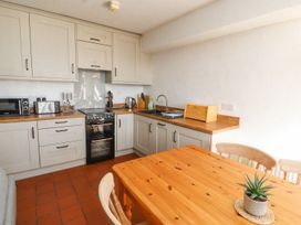 A kitchen with appliances and wooden dining table at Mellfell Cottage near Watermillock