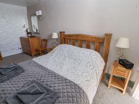 A bedroom with a wooden bed and dresser at Mellfell Cottage near Watermillock