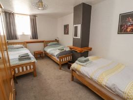 A bedroom with three single beds and a wooden table at Mellfell Cottage near Watermillock