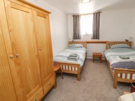 A bedroom with two beds and a wardrobe at Mellfell Cottage near Watermillock