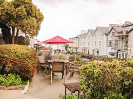 A garden with a table and chairs under an umbrella at Tudno Lodge in Llandudno