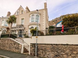 An exterior view of a house with a garden and palm trees at Tudno Lodge in Llandudno