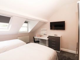 A bedroom with two beds and a desk at Tudno Lodge in Llandudno