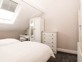 A bedroom with a bed, wardrobe, dresser, and desk at Tudno Lodge in Llandudno