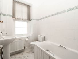 A bathroom with a sink, bathtub, toilet and window at Tudno Lodge in Llandudno