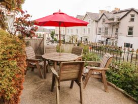 A garden with a table and chairs under an umbrella at Tudno Lodge in Llandudno