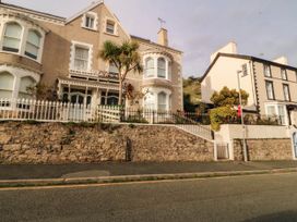 A house with palm trees and a stone wall at Tudno Lodge in Llandudno