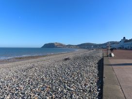 A beach with stones, water, and a promenade at Tudno Lodge in Llandudno