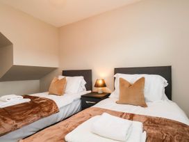 A bedroom with two beds and bedside table at 64 Derwent Road in Whitby