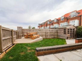 A garden with a wooden table and benches at 64 Derwent Road in Whitby