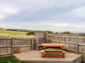 A deck with a wooden bench and fence at 64 Derwent Road in Whitby