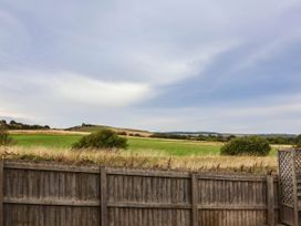 A view of green fields and hills from a fenced area at 64 Derwent Road Whitby
