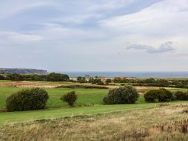 A view of grass fields and trees with the ocean in the background at 64 Derwent Road Whitby