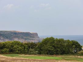 A view of cliffs and the ocean with a golf course in the foreground at 64 Derwent Road Whitby