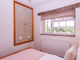 A bedroom with a bed and a window at The Burrow at Aveling Cottage in Lydney