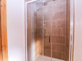 A shower enclosure with tiles and a showerhead at The burrow at Aveling Cottage in Lydney