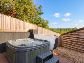A hot tub with a wooden fence and landscape in view at The burrow at Aveling Cottage Lydney