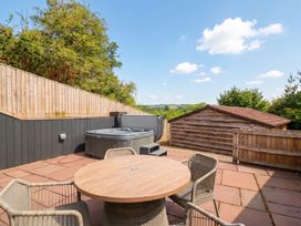 An outdoor area with a hot tub and seating at The Burrow at Aveling Cottage in Lydney