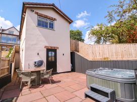 An outdoor area with a hot tub and table at The Burrow at Aveling Cottage Lydney