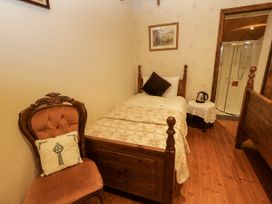 A bedroom with a bed, chair, and shower at Teresa's Cottage