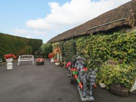 An outdoor area with ivy, flowers, a statue on a stone cart, and a barrel at Teresa's Cottage