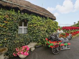 A thatched cottage with ivy and decorative cart at Teresa's Cottage