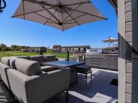 A patio with a sofa and table overlooking a grill at Lakewood Plot 9 in St. Osyth