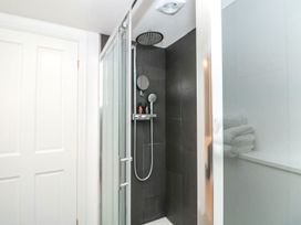 A shower with glass doors and a towel shelf at Shipwrights in Brixham