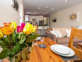 A dining area with flowers on a table and a sofa in the background at Spanish Boathouse in Brixham