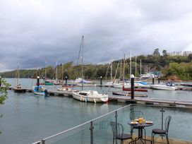An outdoor area with a table and chairs overlooking boats at Spanish Boathouse Brixham